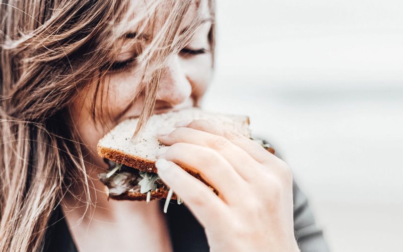 Ein Mädchen beißt genüsslich in ein Butterbrot